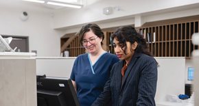 Two people working on a computer together - Health Care Administration